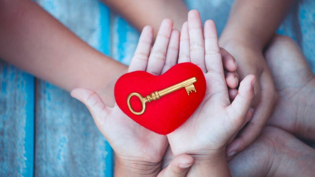 Übereinanderliegende Hände einer Familie mit Herz und Schlüssel - Schlüssel zur Harmonie